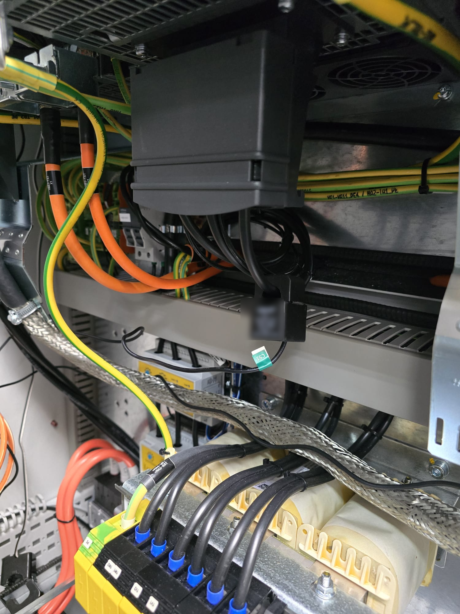 Current sensor clamped onto a machine power lead inside the electrical cabinet